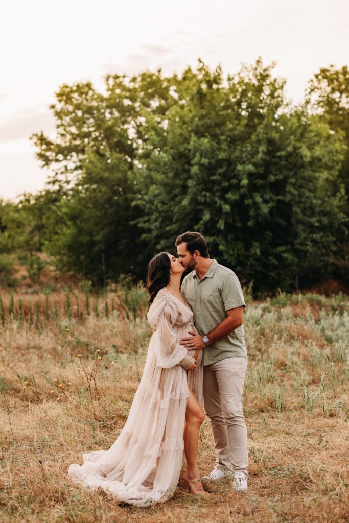 Expecting parents kissing in a field at Northwest Community Park in Keller, TX. 