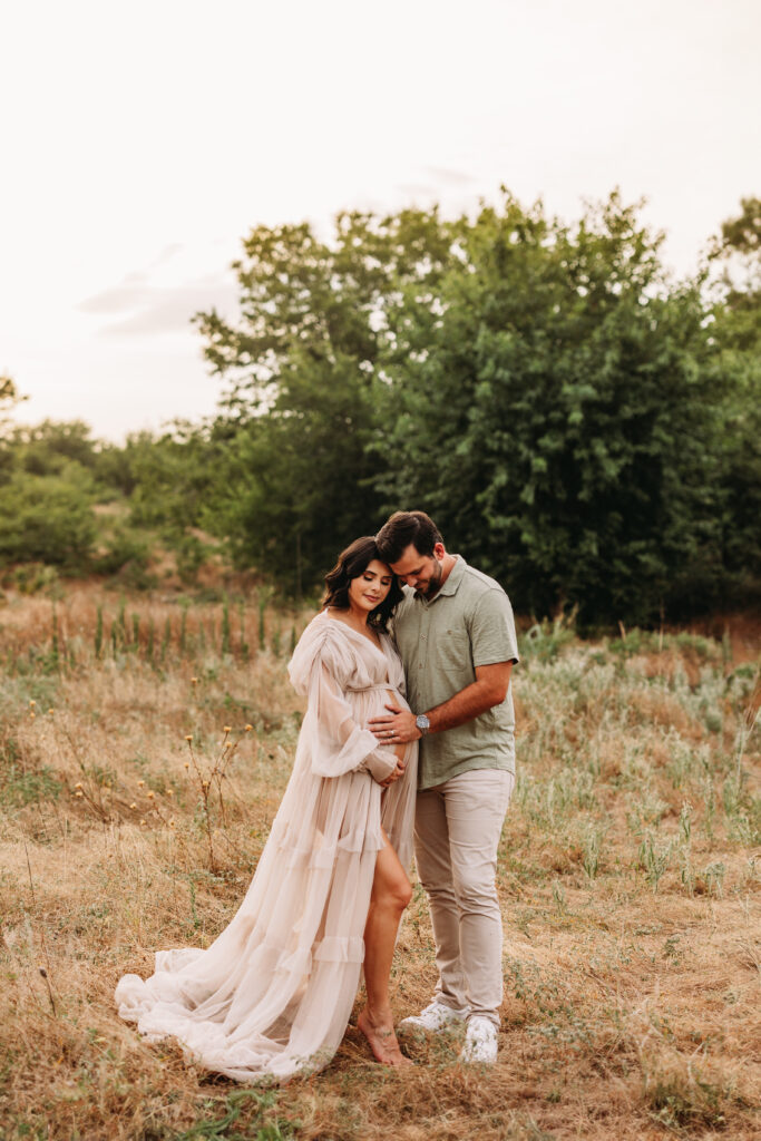 A father placing his hand on his wife's pregnant belly. 